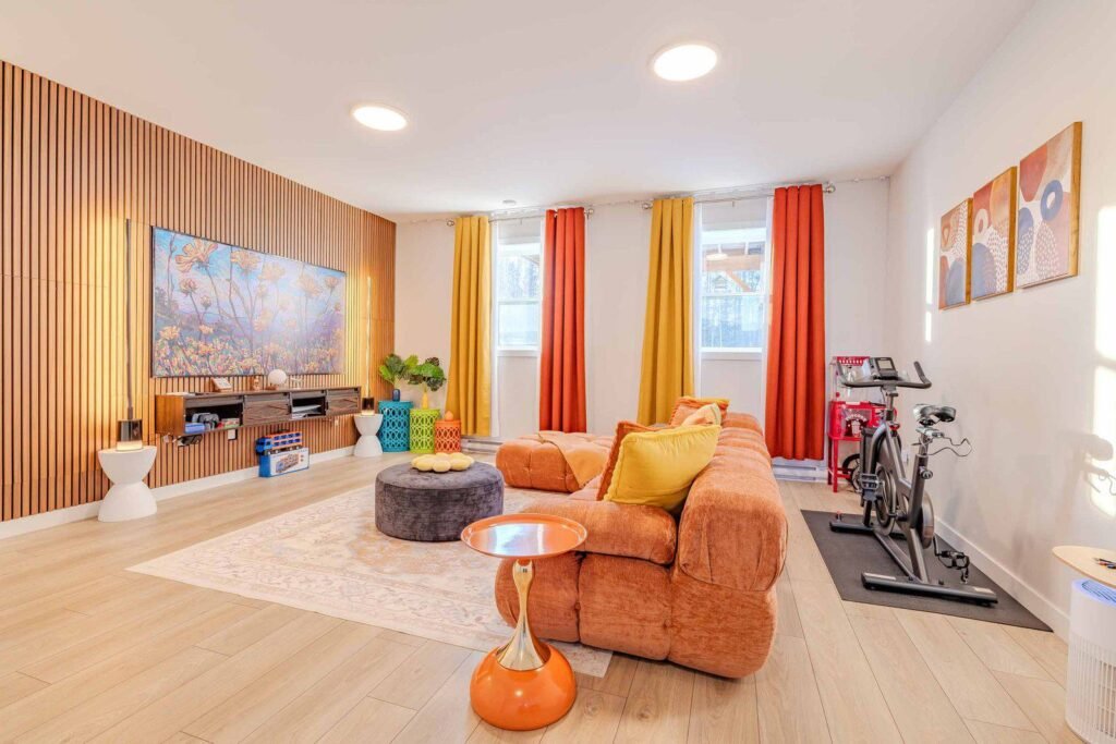 Vibrant game room with orange sofa, exercise bike, and popcorn machine at Starz at Night Luxury Suite