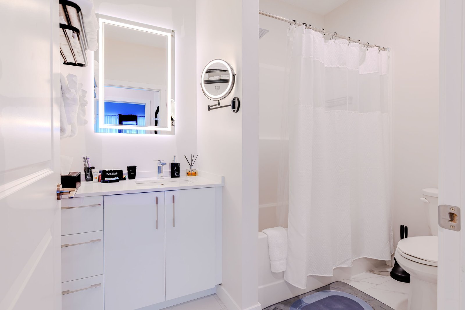 Bathroom vanity with lighted mirror, magnifying mirror, and shower curtain at Starz at Night luxury suite