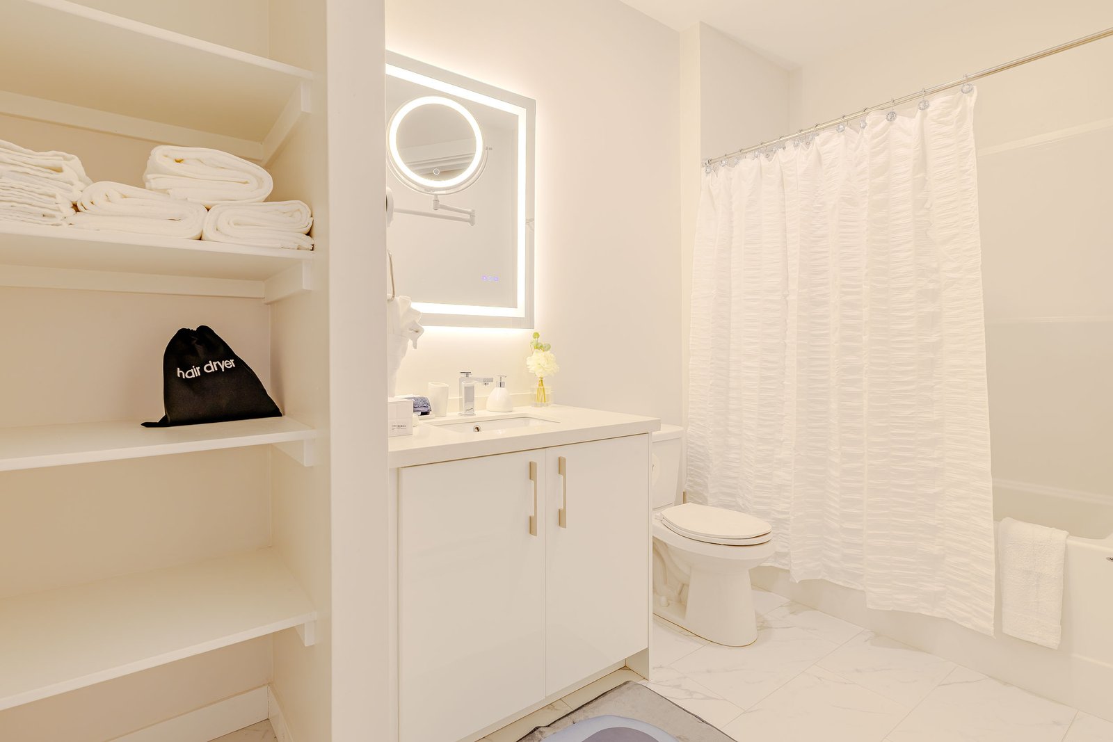 Folded towels and a hair dryer bag on a bathroom shelf at Starz at Night luxury suite