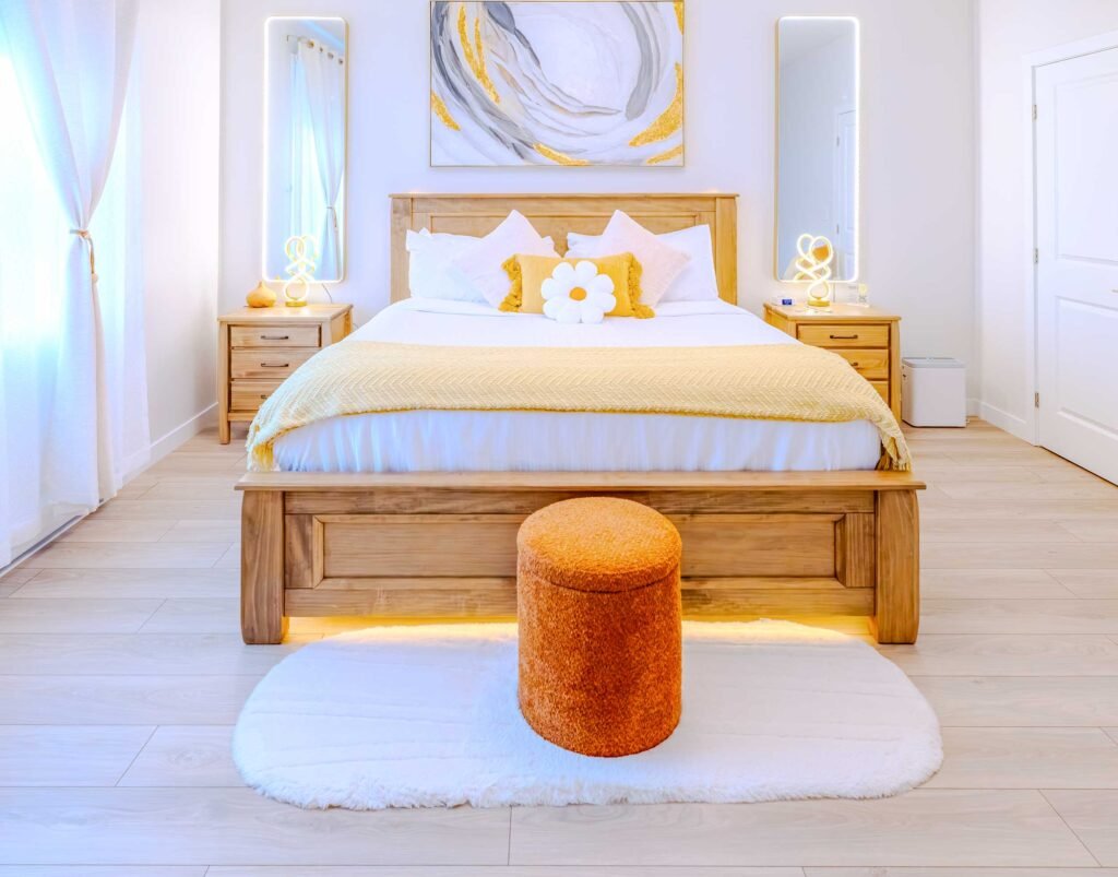 Wooden bed frame with yellow throw blanket and daisy pillow in the master bedroom at Starz at Night luxury suite