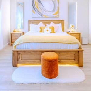Wooden bed frame with yellow throw blanket and daisy pillow in the master bedroom at Starz at Night luxury suite