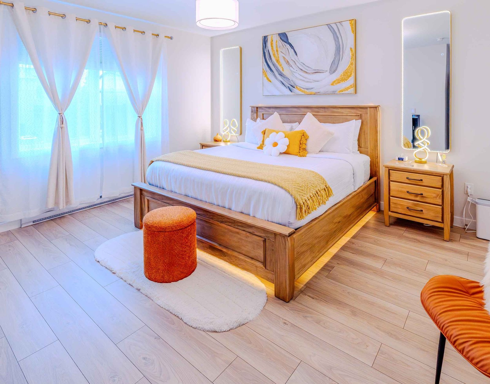 Master bedroom with ambient lit mirrors, nightstands, and yellow throw blanket at Starz at Night luxury suite