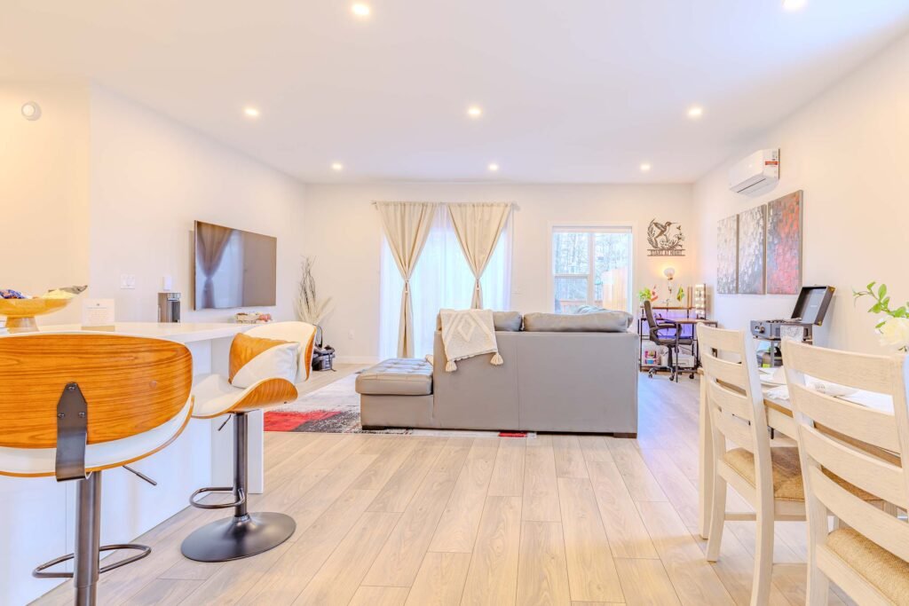 Open-concept living room with gray sofa, TV, and dining table at Starz at Night luxury suite