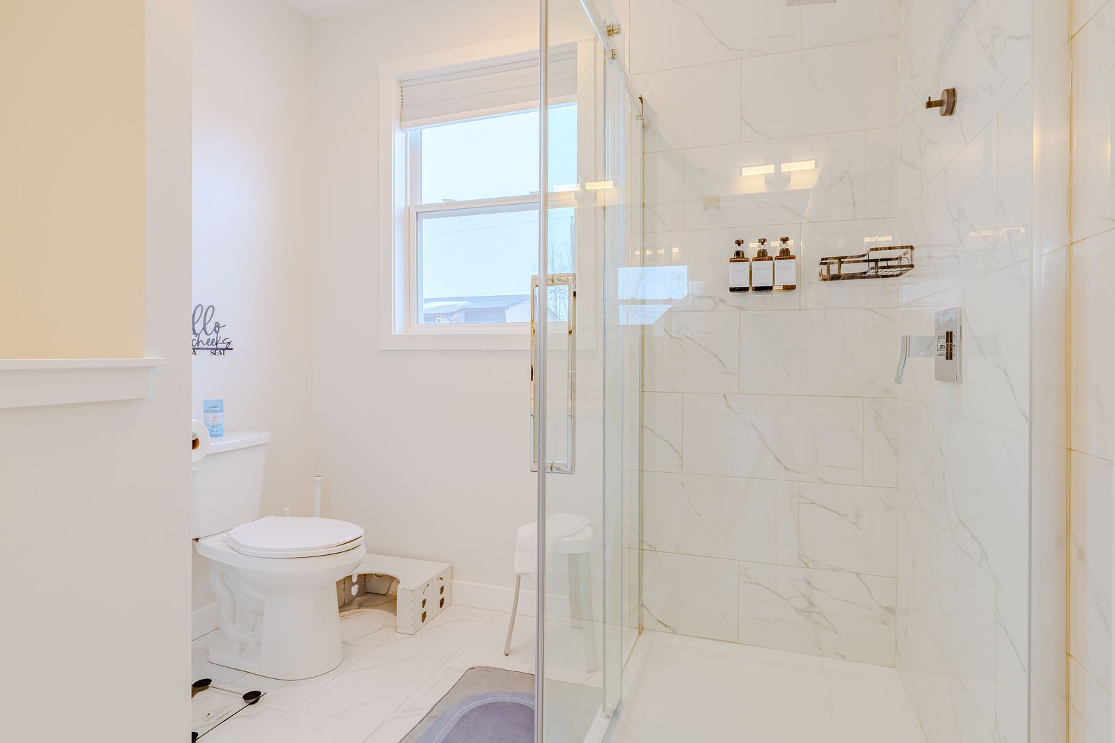 Glass-enclosed marble tile shower with toiletries and shelf at Starz at Night luxury suite