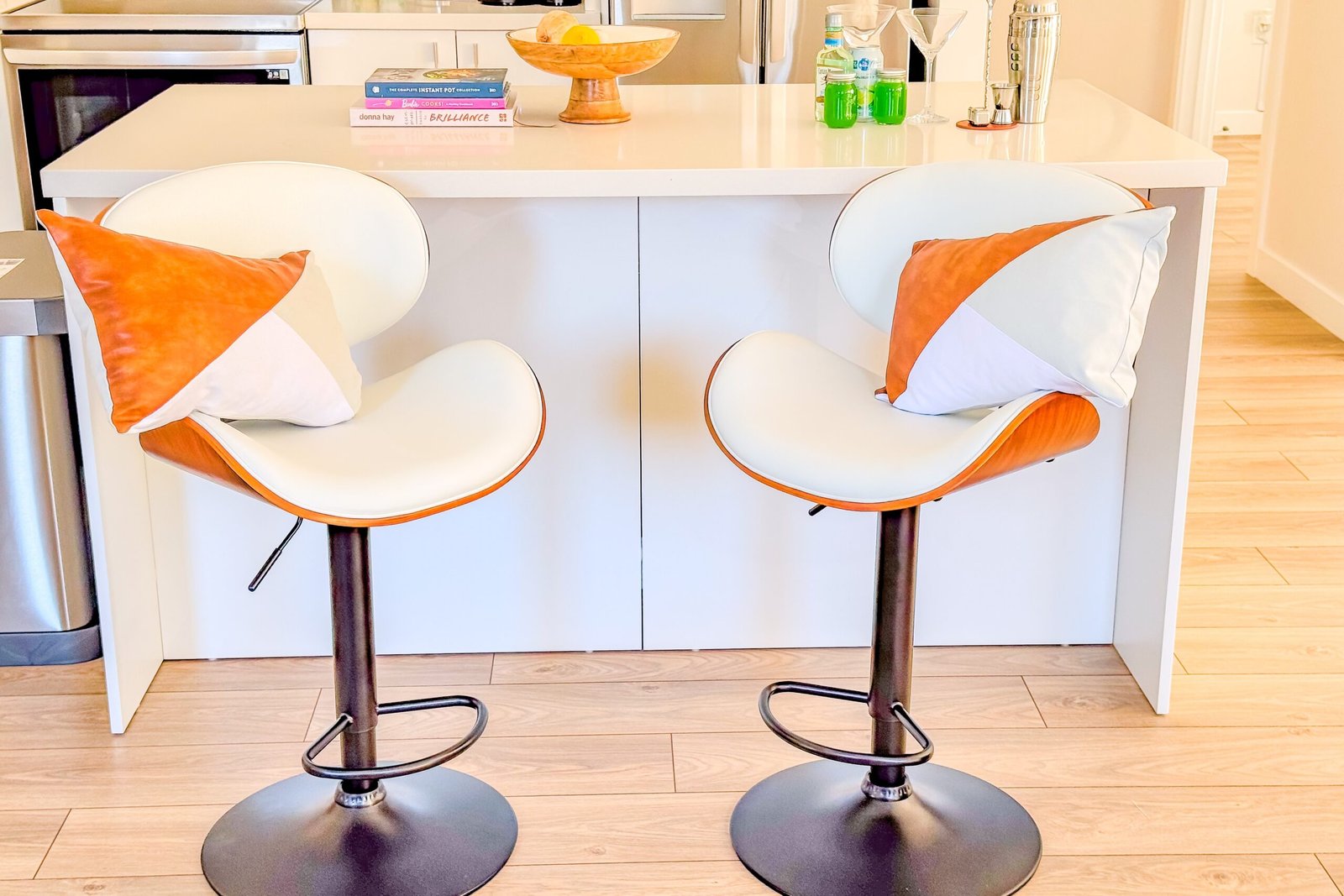 Two orange and white bar stools at the kitchen island with a cocktail shaker and glassware at Starz at Night luxury suite
