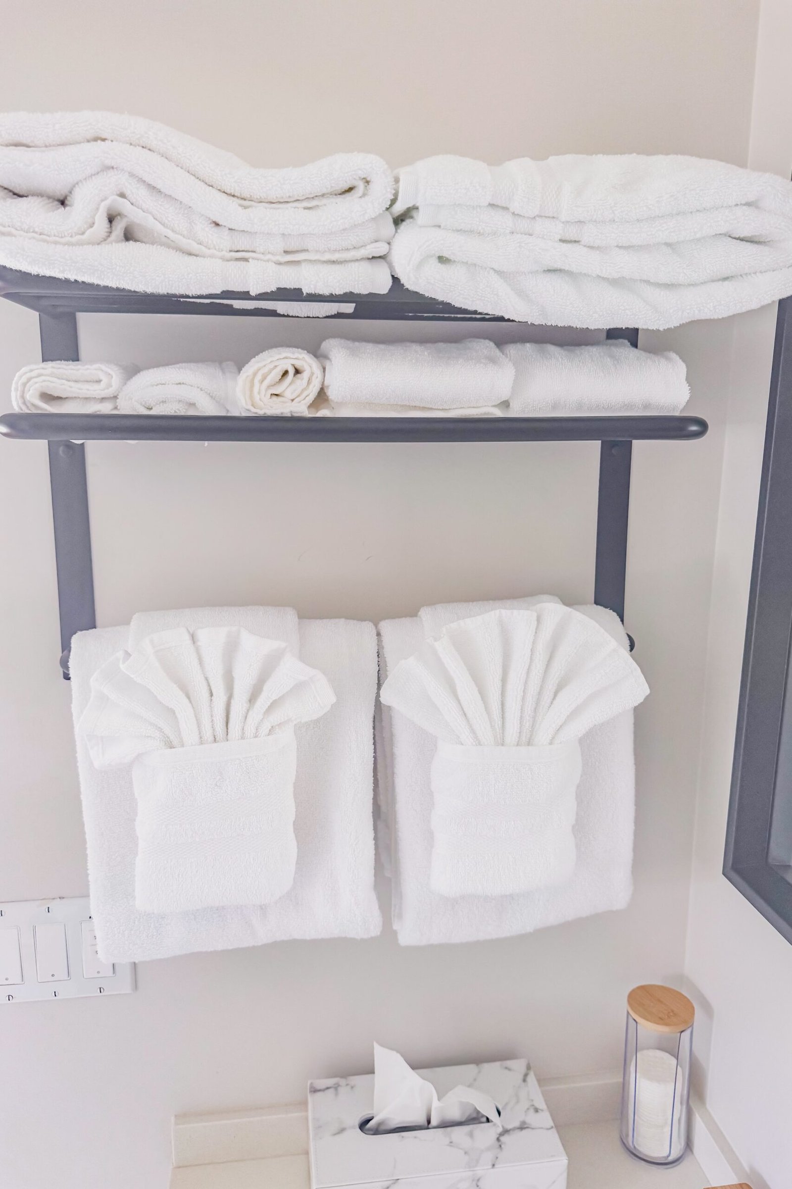 Neatly folded plush white towels stacked on a bathroom shelf at Starz at Night luxury suite