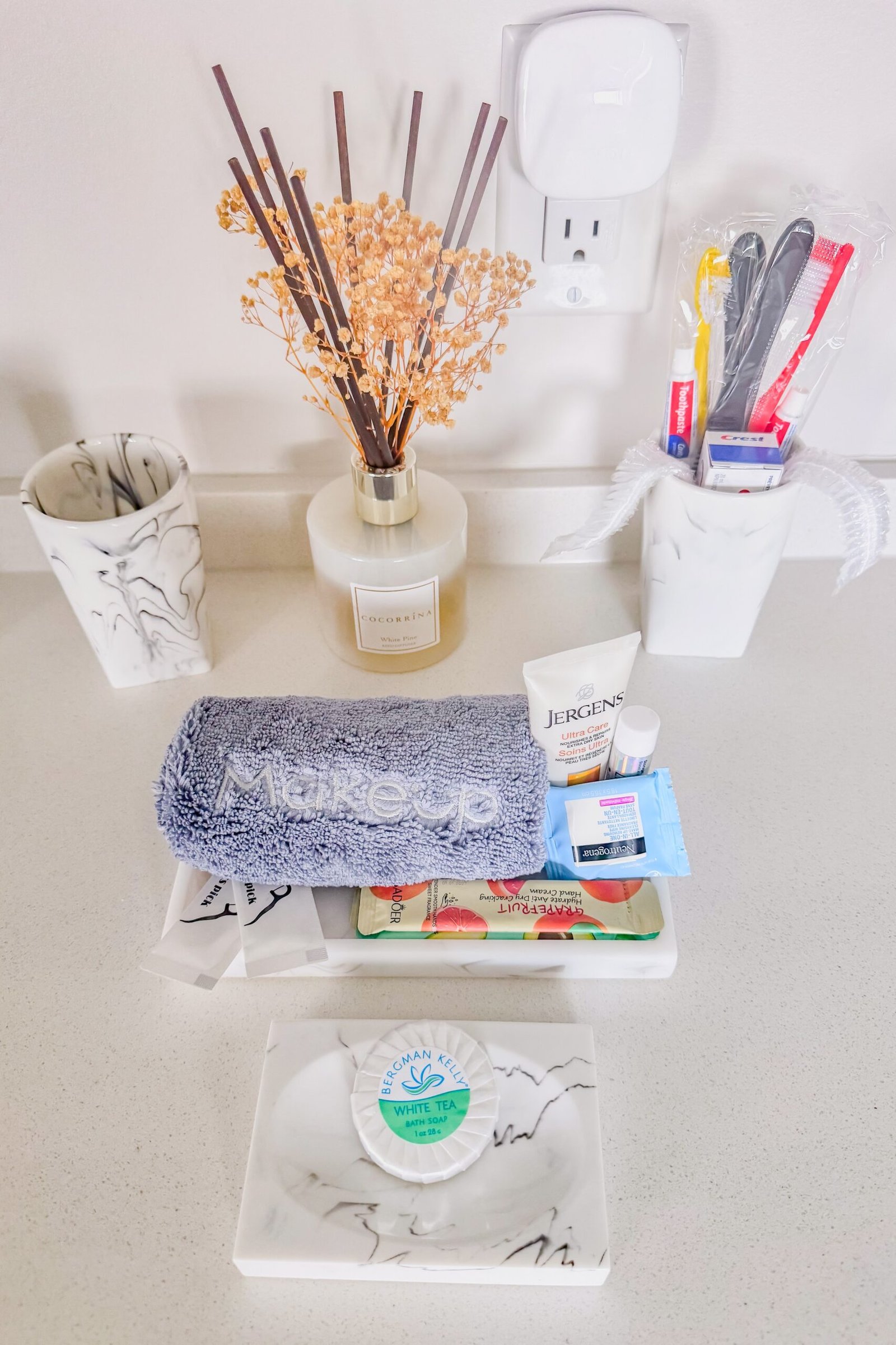 Marble bathroom cups, reed diffuser, and individually wrapped toiletries on the vanity at Starz at Night luxury suite