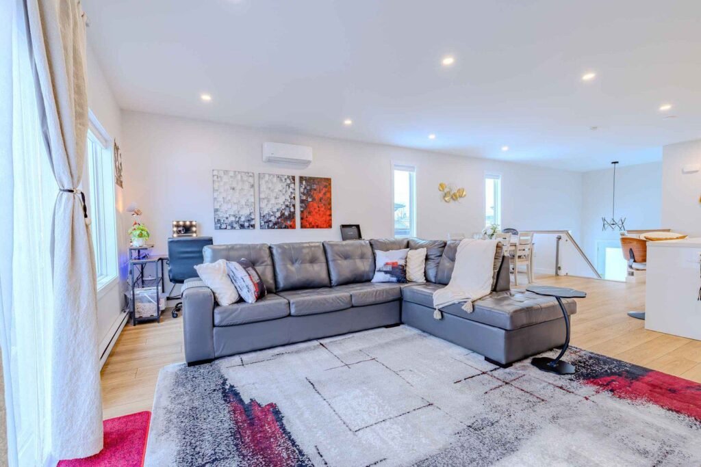 Spacious living room with gray leather sectional, modern art, and open dining view at Starz at Night Luxury Suite