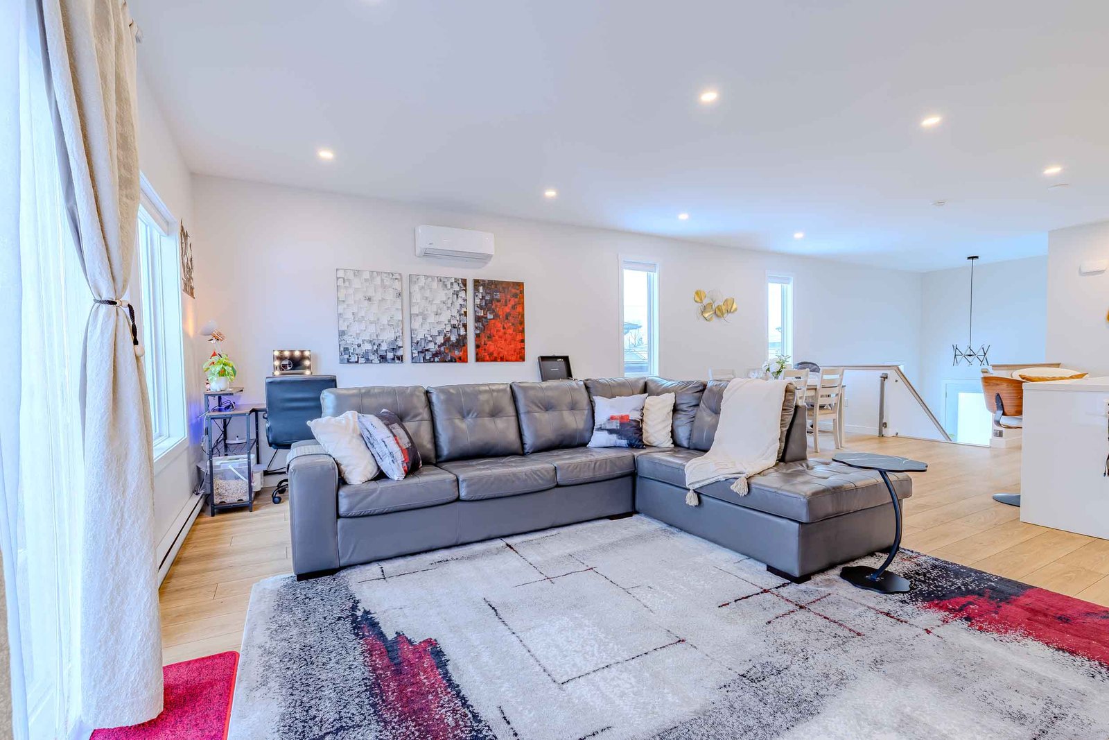 Spacious living room with gray leather sectional, modern art, and open dining view at Starz at Night Luxury Suite