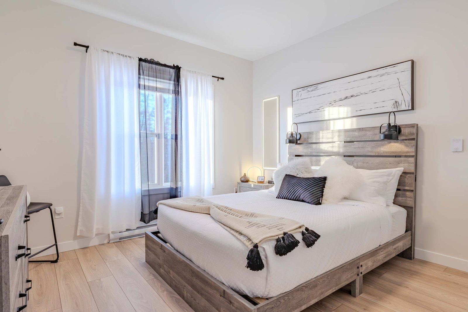 Modern bedroom with plush white bedding, black accents, and wood headboard at Starz at Night Luxury Suite
