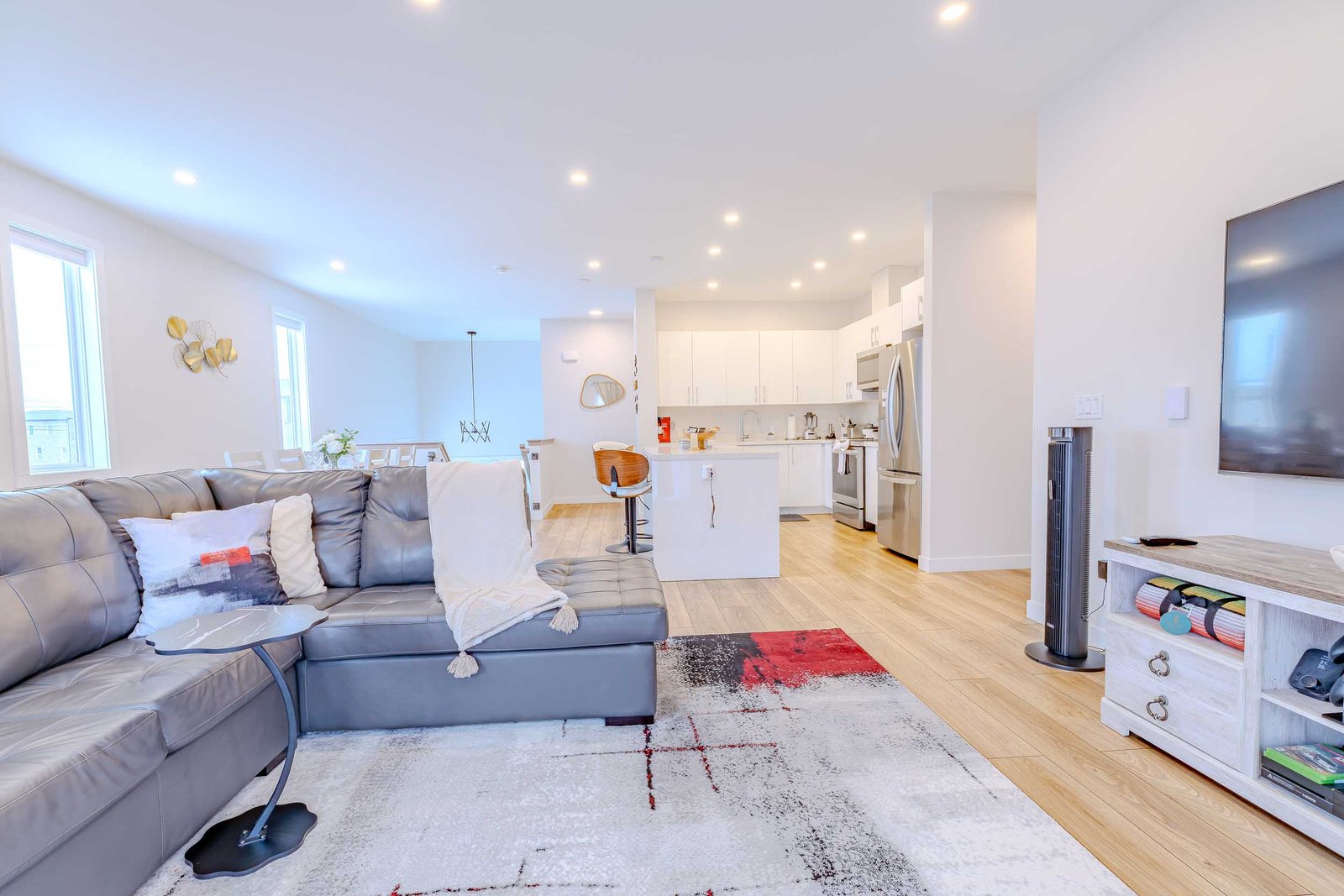 Open-concept living room with leather sectional and modern white kitchen with stainless appliances at Starz at Night Luxury Suite