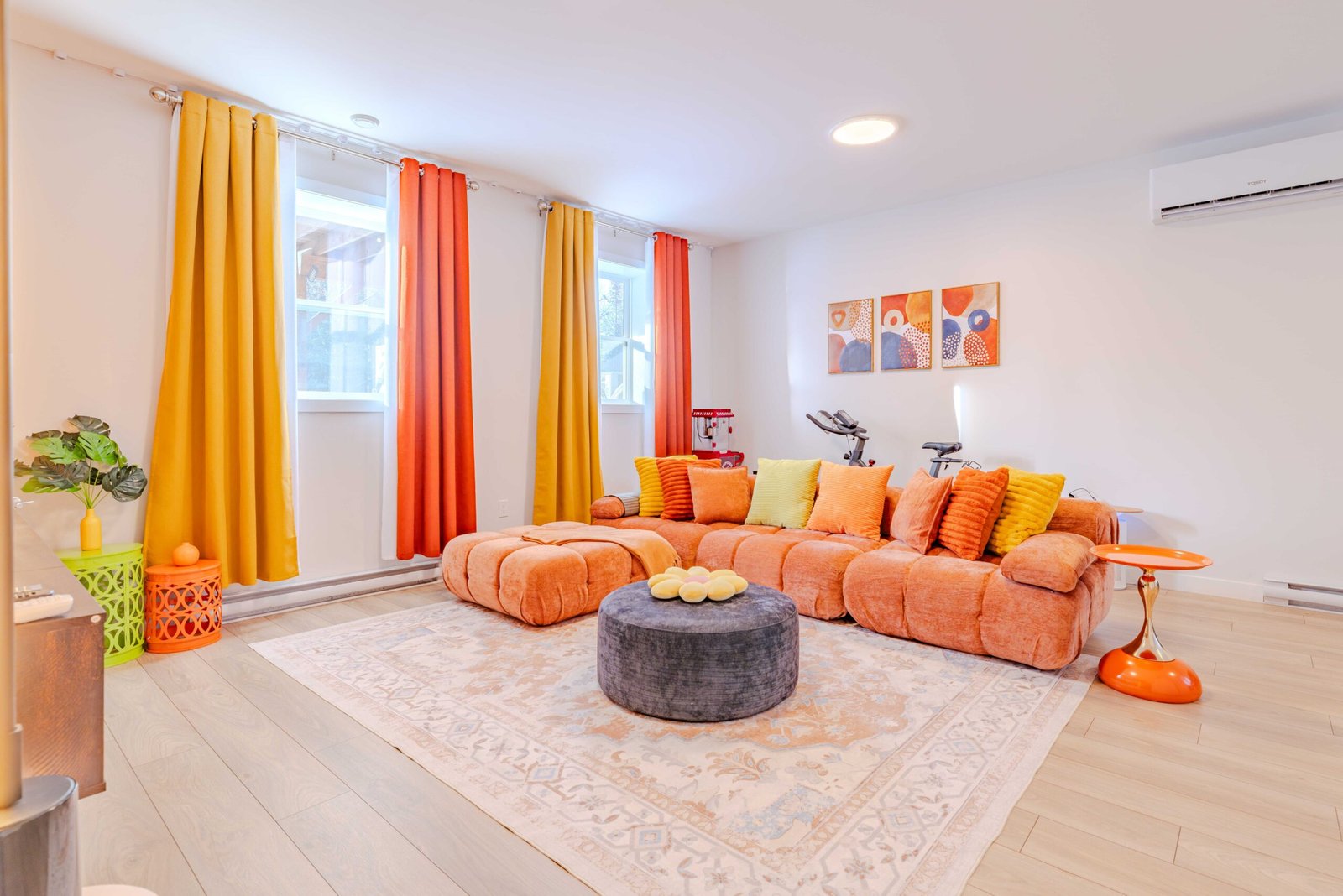 Vibrant orange lounge with sectional sofa, exercise bikes, and popcorn machine at Starz at Night luxury suite in Lantz, Nova Scotia